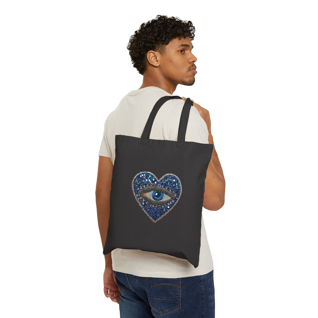 Man carrying a black tote bag with evil eye graphic on a white background